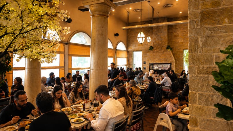 Diners enjoying meals in a bustling restaurant with a decorative lighted tree and stone walls.